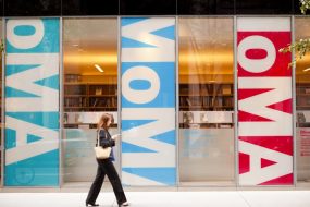 Jeune femme marchant devant la devanture du MoMa à New York